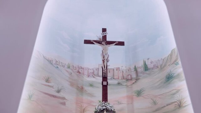 Wooden crucifix mounted over a painted mural of Jerusalem hills inside a church apse