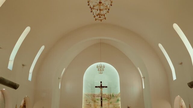 Crucifix under a painted apse arch with chandeliers inside a vaulted church interior