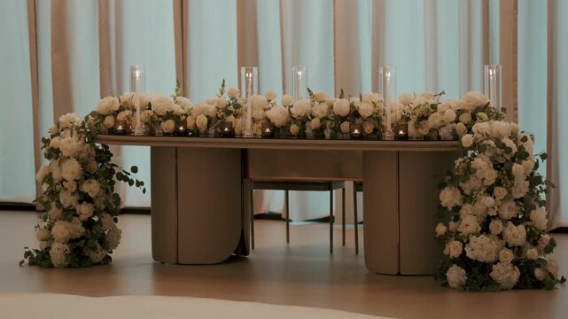 Wedding head table with cascading white roses hurricane candles and votives on a raised floor