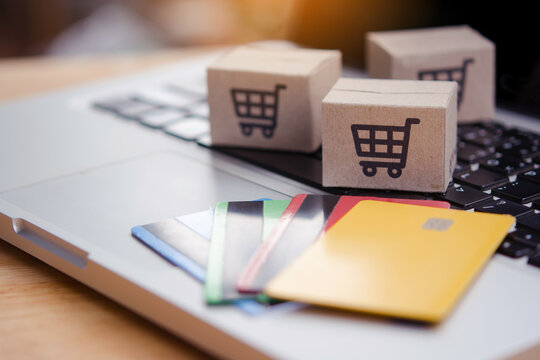Shopping online. Credit card and cardboard box with a shopping cart logo on laptop keyboard. Shopping service on The online web. offers home delivery