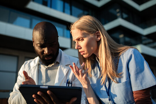 Medical team reviewing patient data on tablet outside hospital