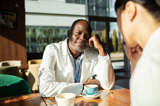 Senior doctor having coffee with colleague in hospital cafeteria