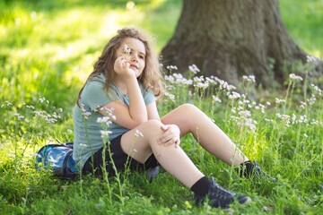 Naklejka premium Meadow flowers frame young girl. Green meadow creates dreamy bokeh. Meadow portrait shows childhood innocence. Meadow scene feels sunny and peaceful.