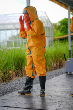 Protective suit chemical protection greenhouse agriculture biosecurity contamination disinfection quarantine worn by worker outdoors cautious stance during safety procedure near crop area