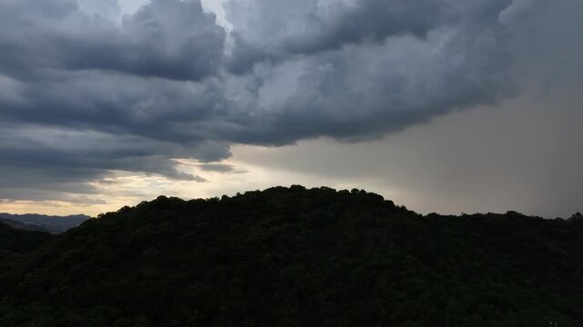 dark cloudy sky over rolling forested hills