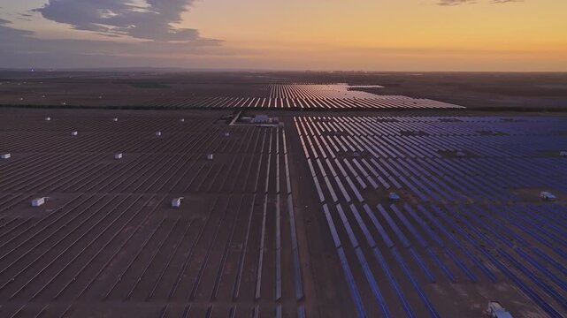 Solar photovoltaic panels at sunrise/sunset; wind turbine power plant; new energy