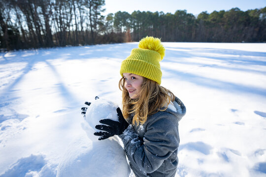 Smiling child playing in snowman outdoor. Concept of winter childhood happiness, outdoor fun, and winter seasonal joy. Kid winter active winter lifestyle. Child play with snow during New Year holiday.