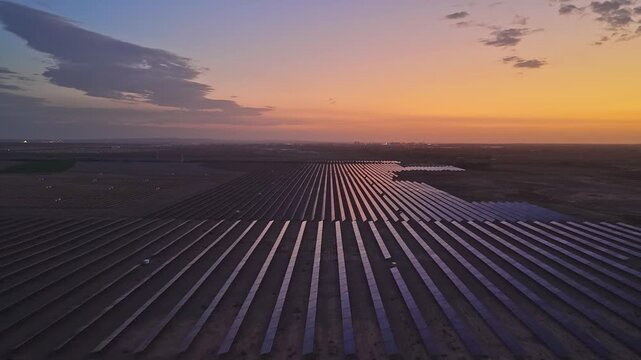 Solar photovoltaic panels at sunrise/sunset; wind turbine power plant; new energy