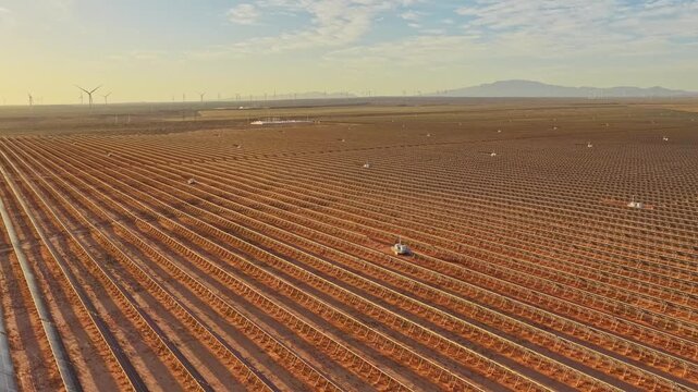 Solar photovoltaic panels at sunrise/sunset; wind turbine power plant; new energy