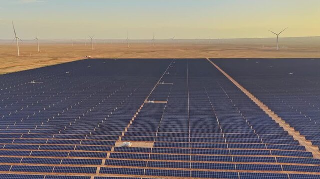 Solar photovoltaic panels at sunrise/sunset; wind turbine power plant; new energy
