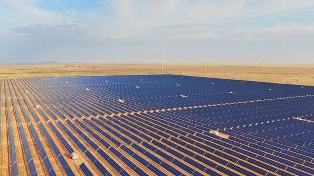 Solar photovoltaic panels at sunrise/sunset; wind turbine power plant; new energy