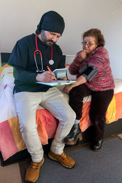 Healthcare worker checking senior woman's blood pressure at home