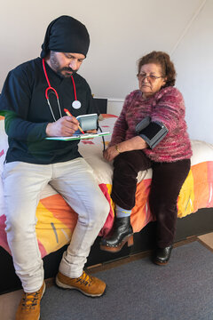 Healthcare worker examining older woman during home visit
