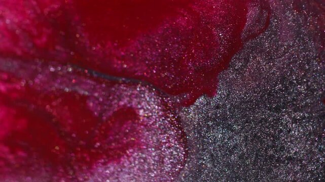 Shimmer paint wave. Shiny particles. Defocused red purple silver color ink texture glitter spatter floating on abstract acrylic background.
