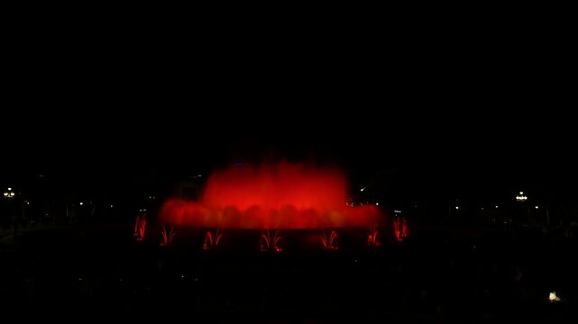 Orange and red illuminated fountain glows brightly against the dark Barcelona night, Magic Fountain of Montjuic