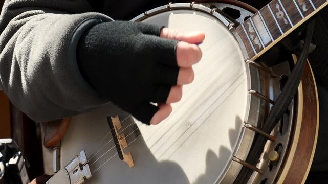 Musician's hand plucks strings on a banjo during a performance, close details