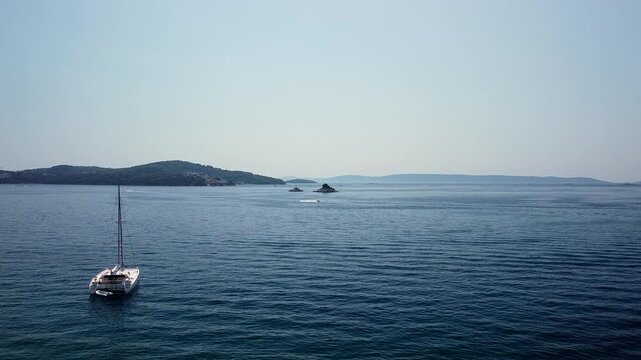 Sailboat rests on calm Adriatic Sea near Seget Vranjica, Trogir, Croatia, aerial stunning dolly backdrop