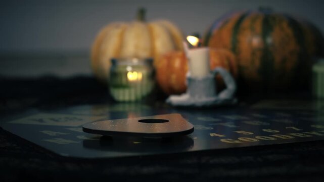 Spirit board with pumpkins and candles close up zoom slow motion shot selective focus