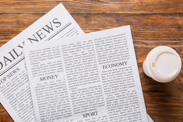 Global news and economic updates daily newspaper with money and sport sections coffee cup on wooden table top view