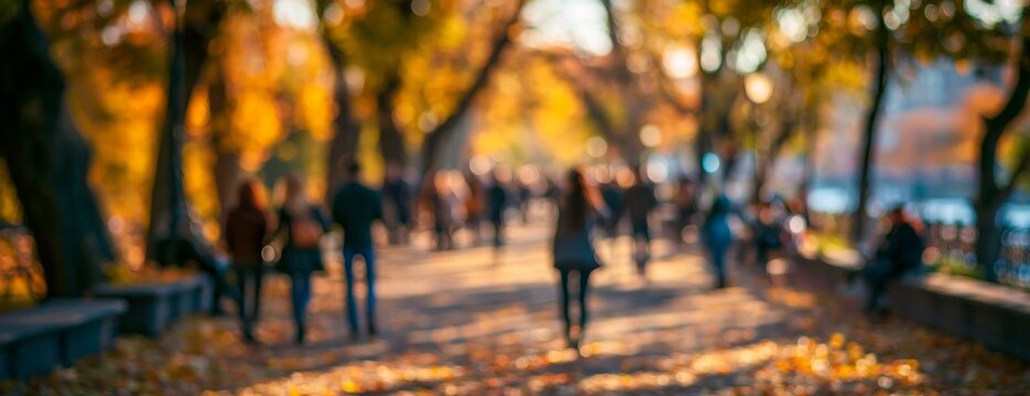 People walking in an autumn park with golden leaves, blurred background  