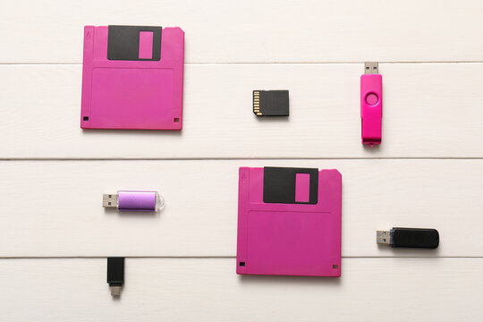 Evolution of data storage technology floppy disks usb flash drives and sd card on white wooden background