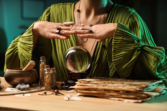 Fortune teller with crystal ball reading future at table in room, closeup