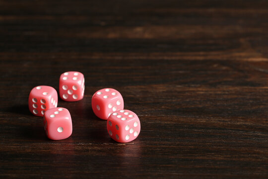 Pink game dices on wooden background