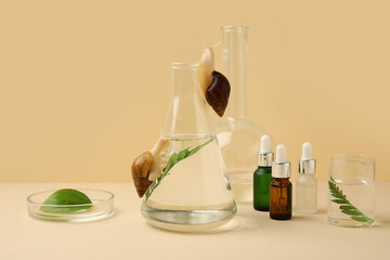 Laboratory flasks of samples with Achatina snails and cosmetic products on beige background © Pixel-Shot