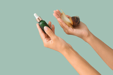 Female hands with snail and bottle of serum on green background © Pixel-Shot