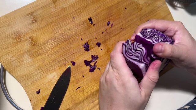 Horizontal 4K video. Top view. Female hand close up. Woman breaks head of purple red cabbage with her hands on wooden cutting board for soup, salad, dinner, lunch. Concept of harvest, food, eat, diet