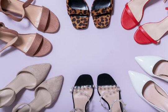 Different types of shoes arranged in a circle on a light purple background during a product display