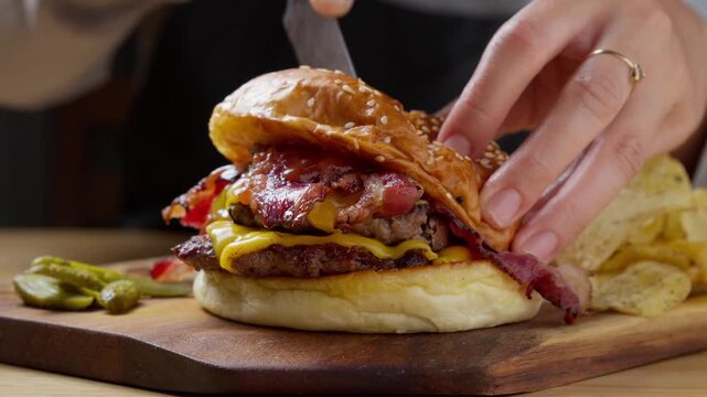 Cutting a loaded double bacon cheeseburger in half with a knife
