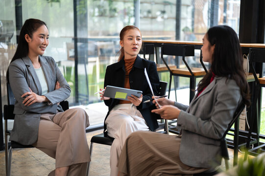 Business meeting with women discussing strategy and reviewing data on tablet