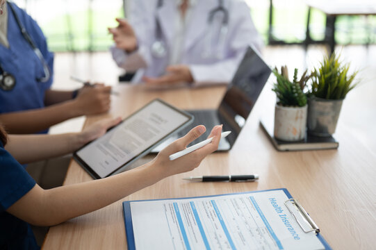 Healthcare professionals discussing medical records and insurance information using tablet