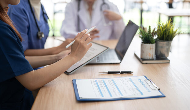 Healthcare professionals discussing medical information with tablet and health insurance documents