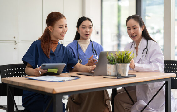 Healthcare team discussing patient care using laptop and tablet in modern office