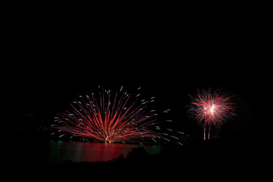 Vibrant Fireworks Exploding Over Lake at Night with Dark Sky and Copy Space