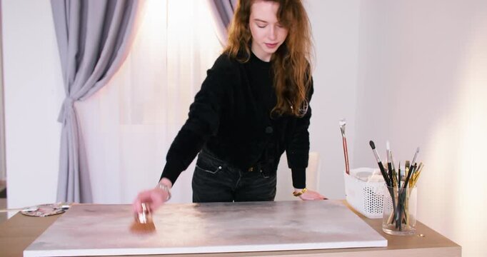 Creative hobby. Art paint. Female professional master enjoying handmade color drawing using canvas paintbrush at workspace.