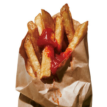 Fries with ketchup wrapped in paper served in a casual setting during lunch or snack time