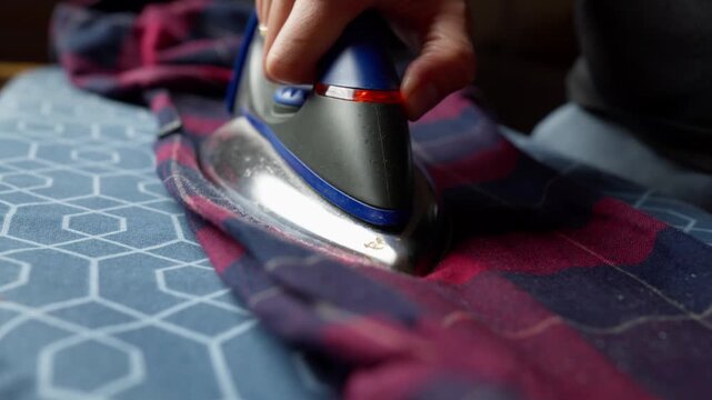 Ironing a plaid shirt to remove wrinkle, with steam rising