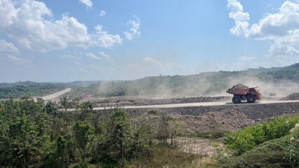 Large mining dump truck hauling materials across wide open pit mining haul road © faaqiihh