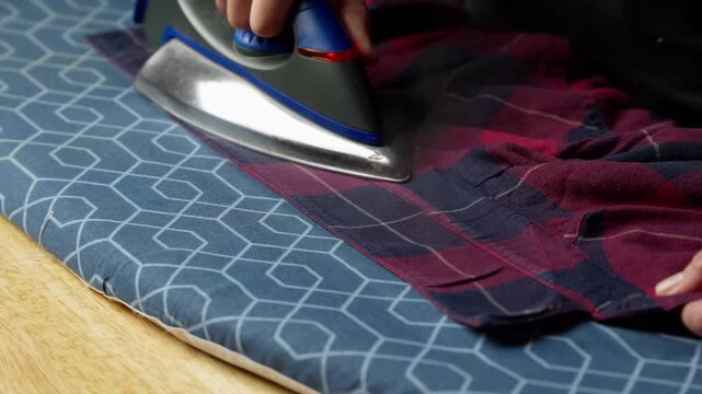 Ironing a plaid shirt to remove wrinkle, with steam rising