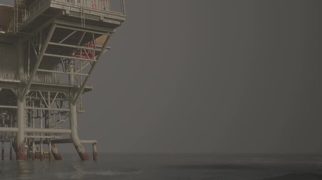 A large oil platform is shown above the water in the ocean. The sky is cloudy and the environment looks industrial. The structure is partially submerged in the sea.