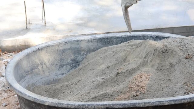 mixing of cement and sand in large containers for use in construction demonstrates traditional material preparation and building processes.