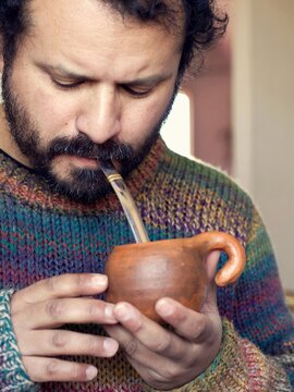Close-up of a South American man drinking from and enjoying his clay bowl of mate gourd