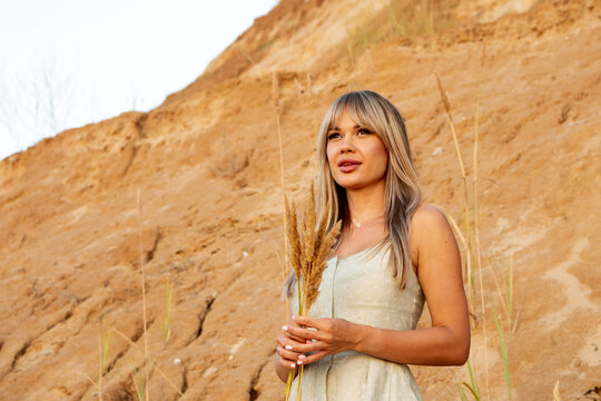 Woman Posing With Pampas Grass Against Sandy Cliff