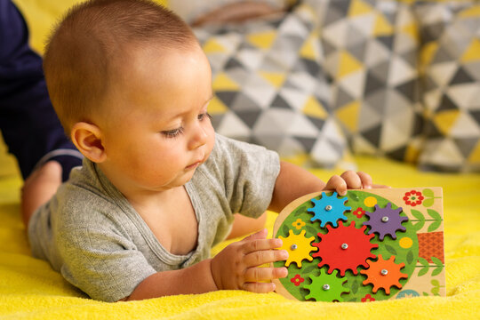 Baby Holding Colorful Wooden Gear Puzzle During Tummy Time