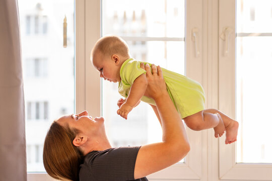 Mother Lifts Baby Boy High During Playful Home Moment