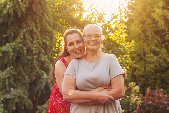 Adult Daughter Hugging Smiling Mother in Golden Garden