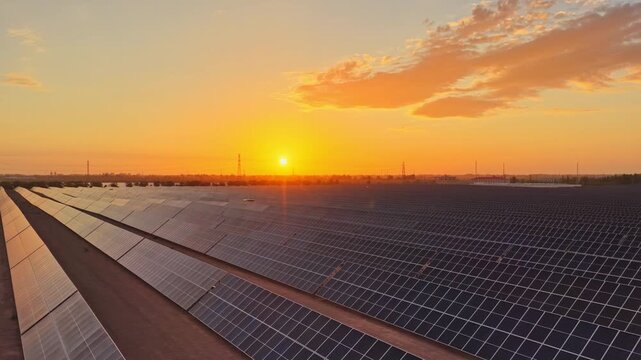 Solar photovoltaic panels at sunrise/sunset; wind turbine power plant; new energy